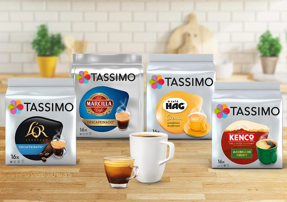 TASSIMO coffee pods, a cup, and espresso on a wooden table.