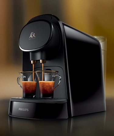Two espresso machines brewing rich L'OR Espresso into elegant glass cups, filling the air with aroma.
