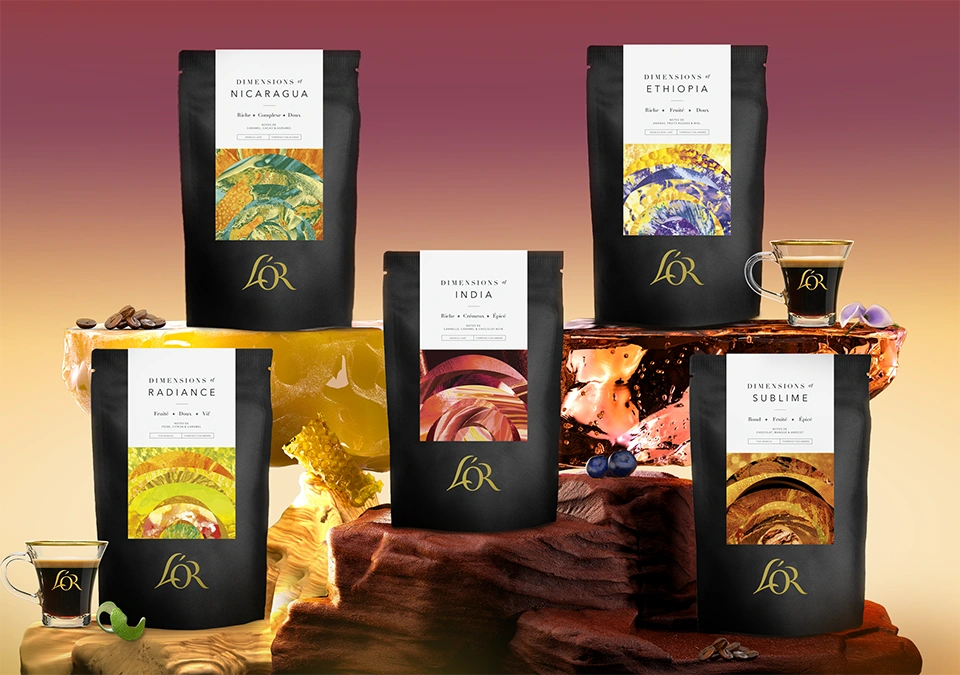 Collection L’OR Dimensions – cinq paquets de café premium présentés avec tasses espresso.