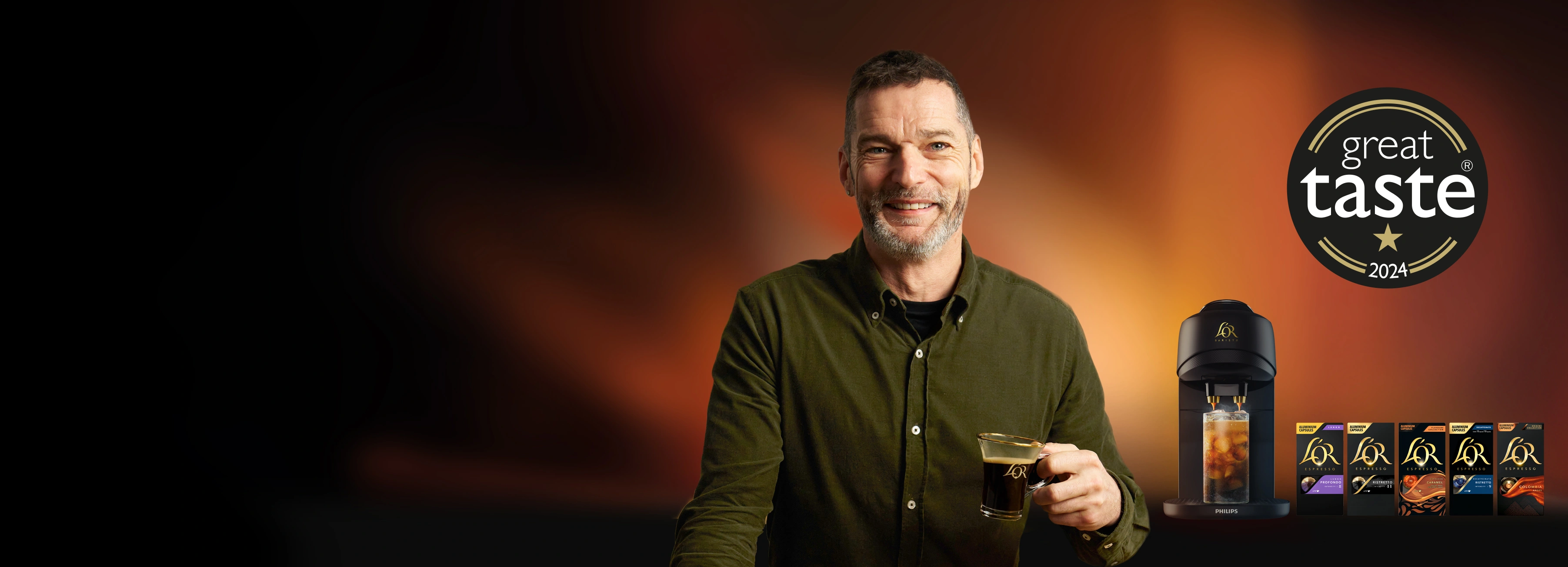 Fred Sirieix with L'Or espresso cup beside L’OR Barista Absolu machine and various capsule flavors, featuriung 'Great Taste 2024' logo