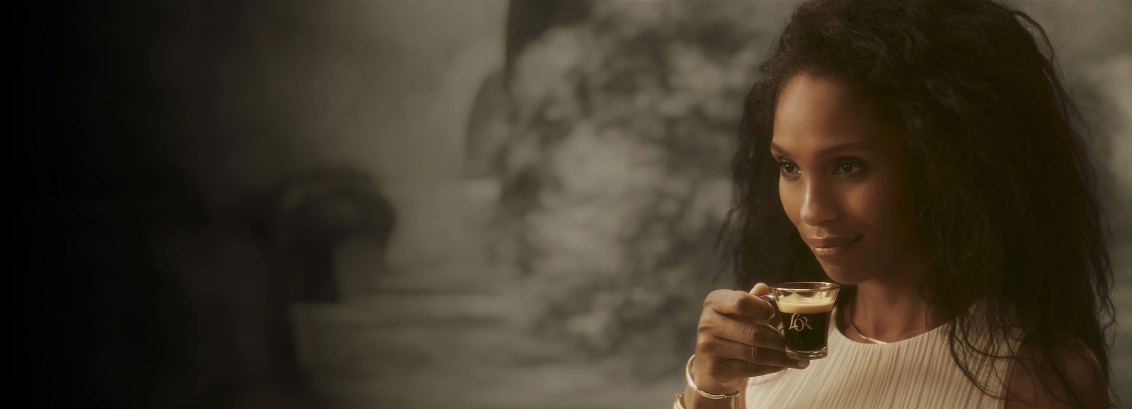 A woman carrying a cup of rich L'OR Espresso coffee