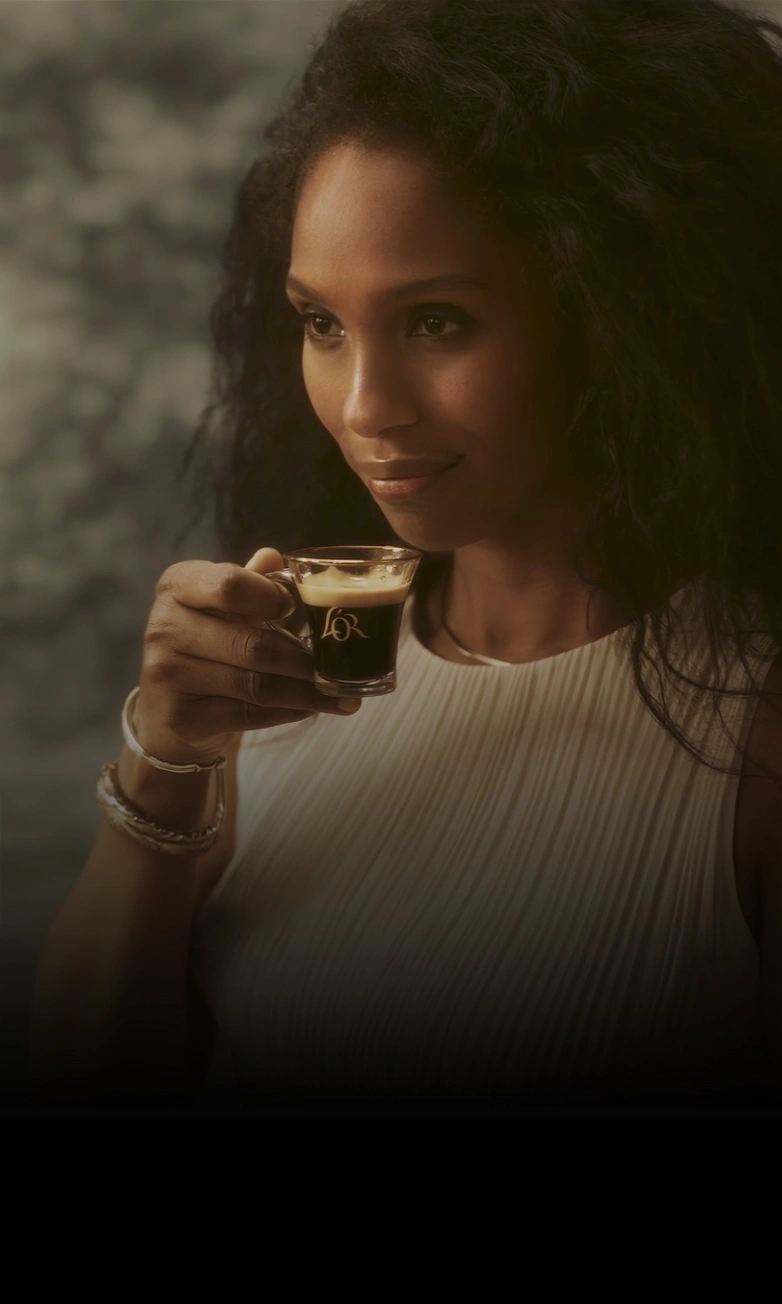 A woman carrying a cup of rich L'OR Espresso coffee