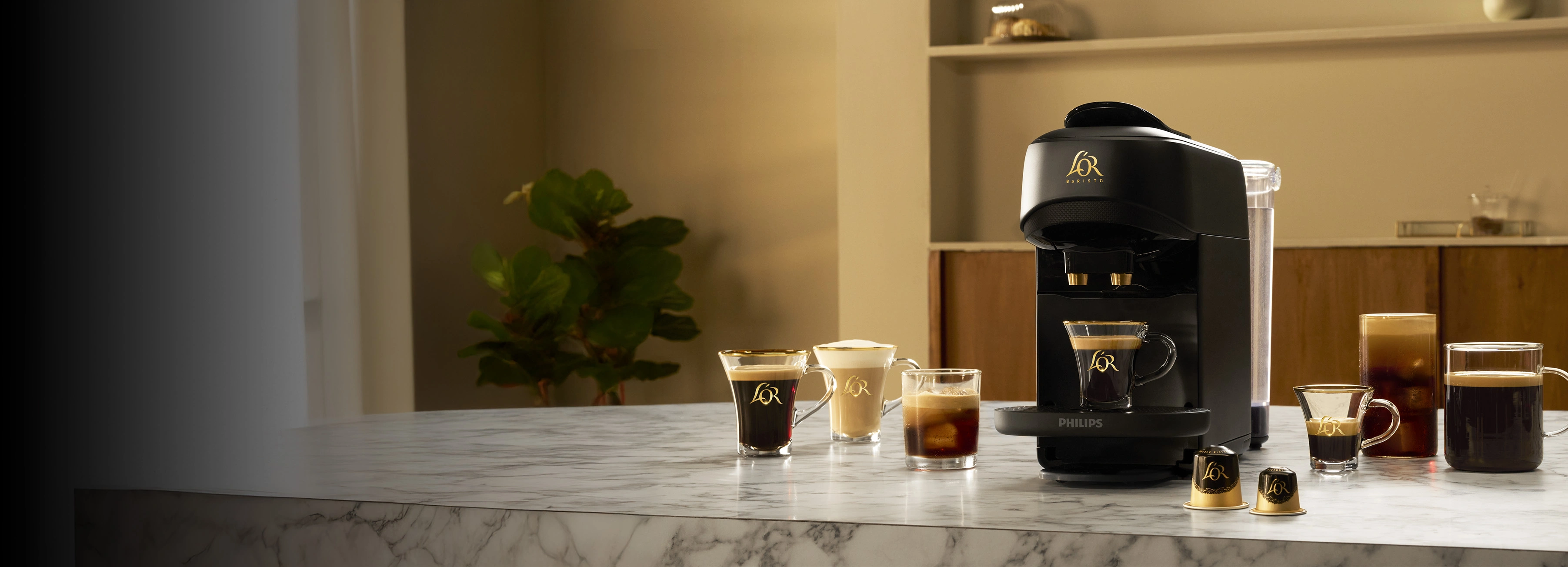 L'OR BARISTA-koffiemachine en verschillende koffiekopjes op een marmeren aanrecht.