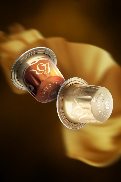 Deux capsules L'OR de la collection Flavors, Caramel et Vanilla, en lévitation. Un tissu de soie dorée en arrière-plan.