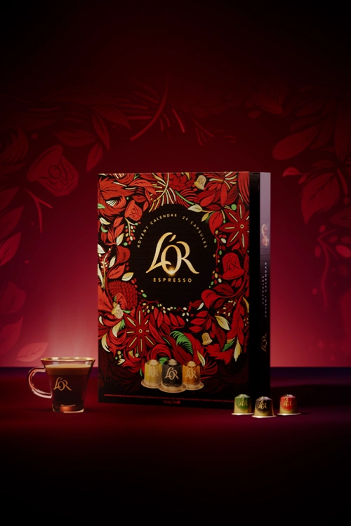 L'OR Advent Calendar 2025, espresso cup and few capsules on a red background.