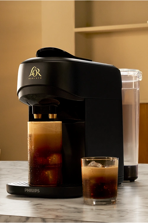 L'OR BARISTA Absolu black machine with different coffee drinks on a marble table.