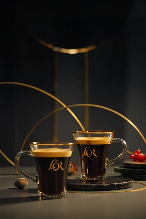Two L'OR lungo cups on a dark and elegant table.