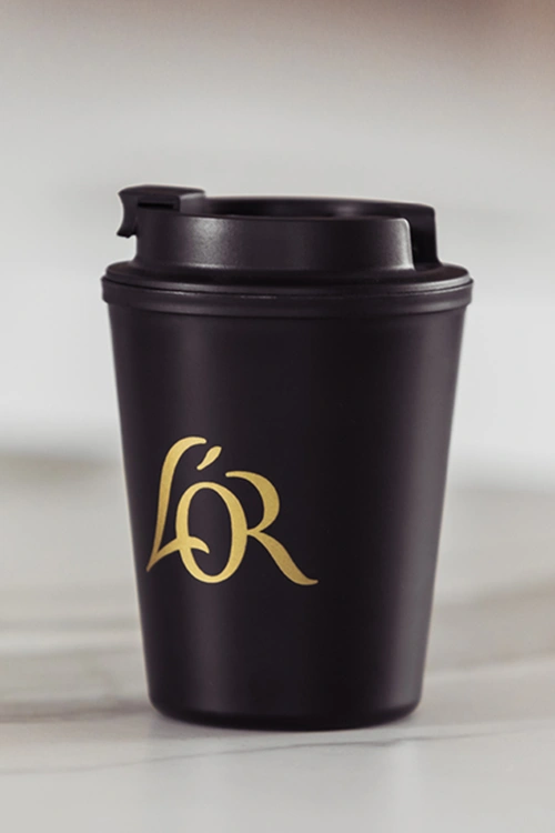 L'OR black reausable cup on a marble table.