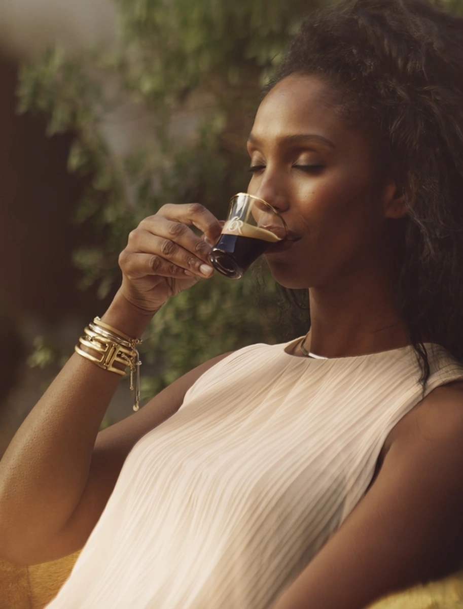 Young woman savouring L'OR coffee in a mystical garden.