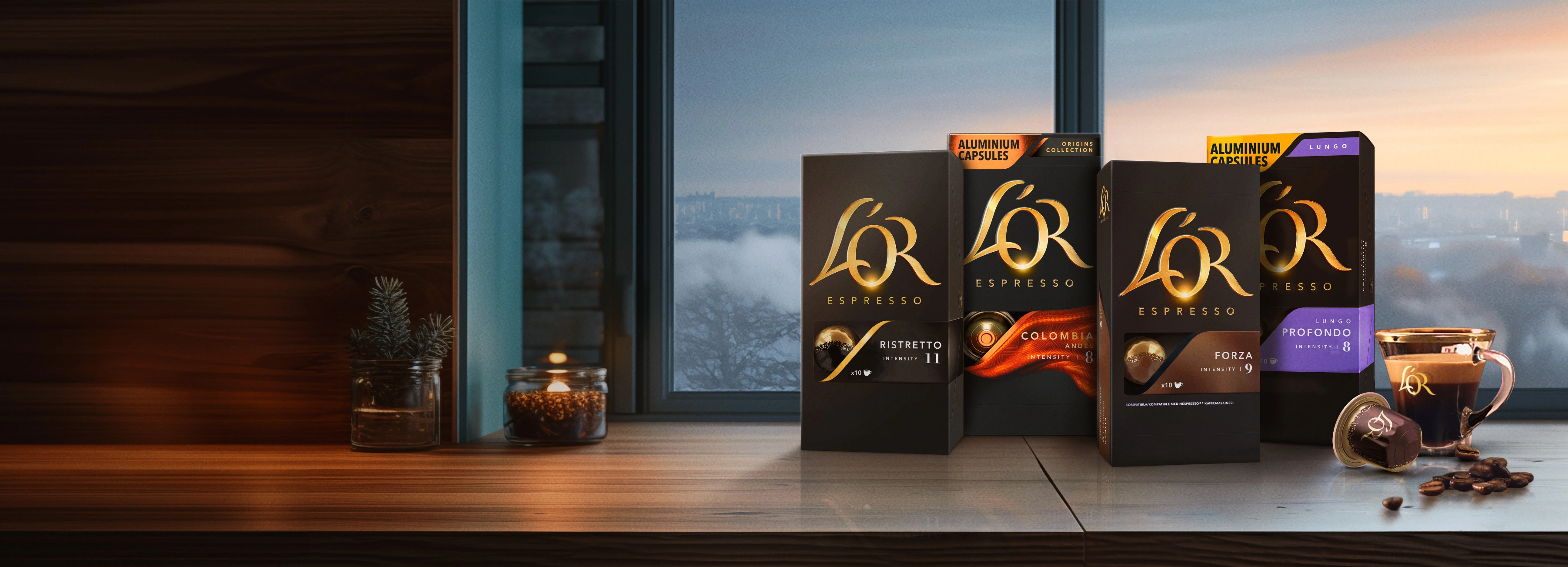 L'OR Ristretto, Colombia, Forza and Profondo packs, coffee cup and capsules on a wooden table with winter window background.