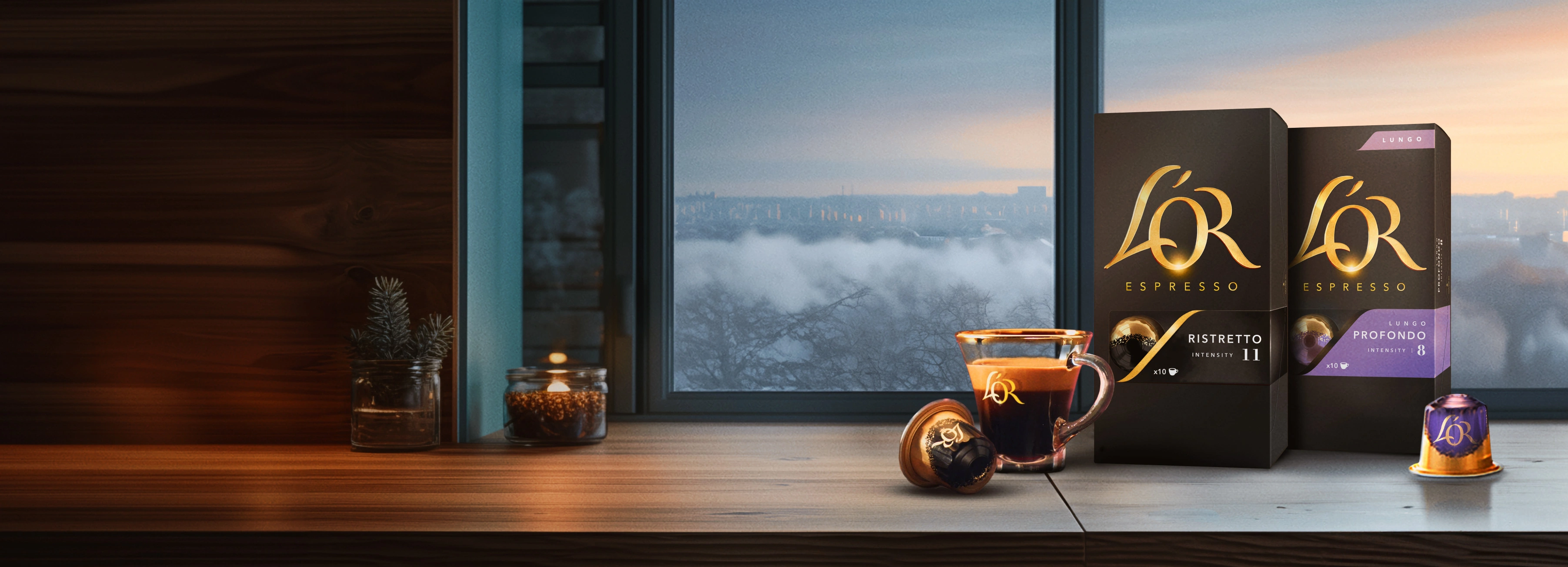 L'OR Ristretto and Profondo packs with coffee cup, capsules on a wooden table with winter window background. 