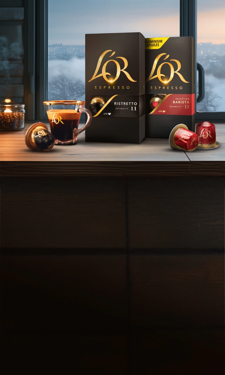 L'OR Ristretto and Barista 13 packs with coffee cup, capsules on a wooden table with winter window background.