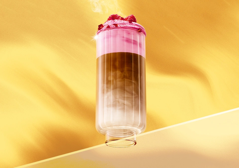 Kaltes Kaffeegetränk mit rosa Schaum im hohen Glas