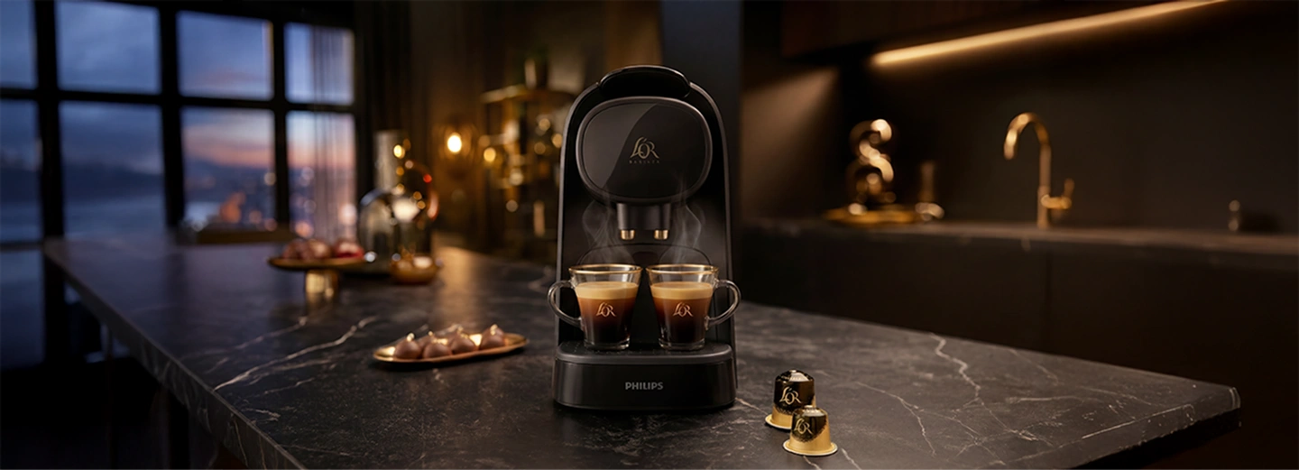 Máquina de café L'OR en una cocina con varias tazas de café preparadas y cápsulas alrededor
