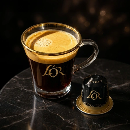 Taza de espresso L'OR servida con cápsulas en primer plano sobre una mesa