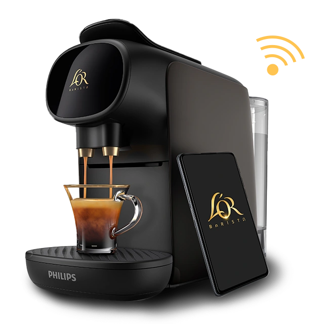 Black L’OR BARISTA Creatif machine pouring a single espresso, with a smartphone displaying the L’OR logo placed beside it.