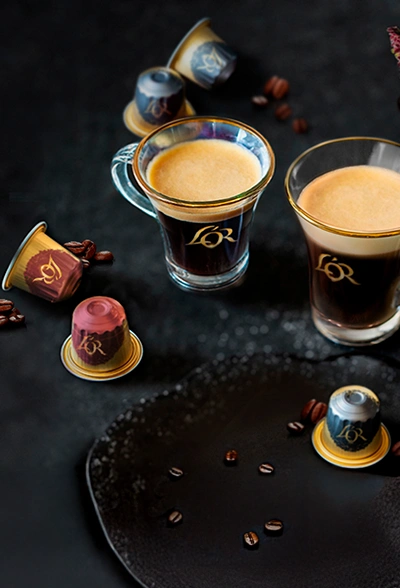 L'OR Espresso coffee capsules next to crema-rich Espresso and Lungo glasses