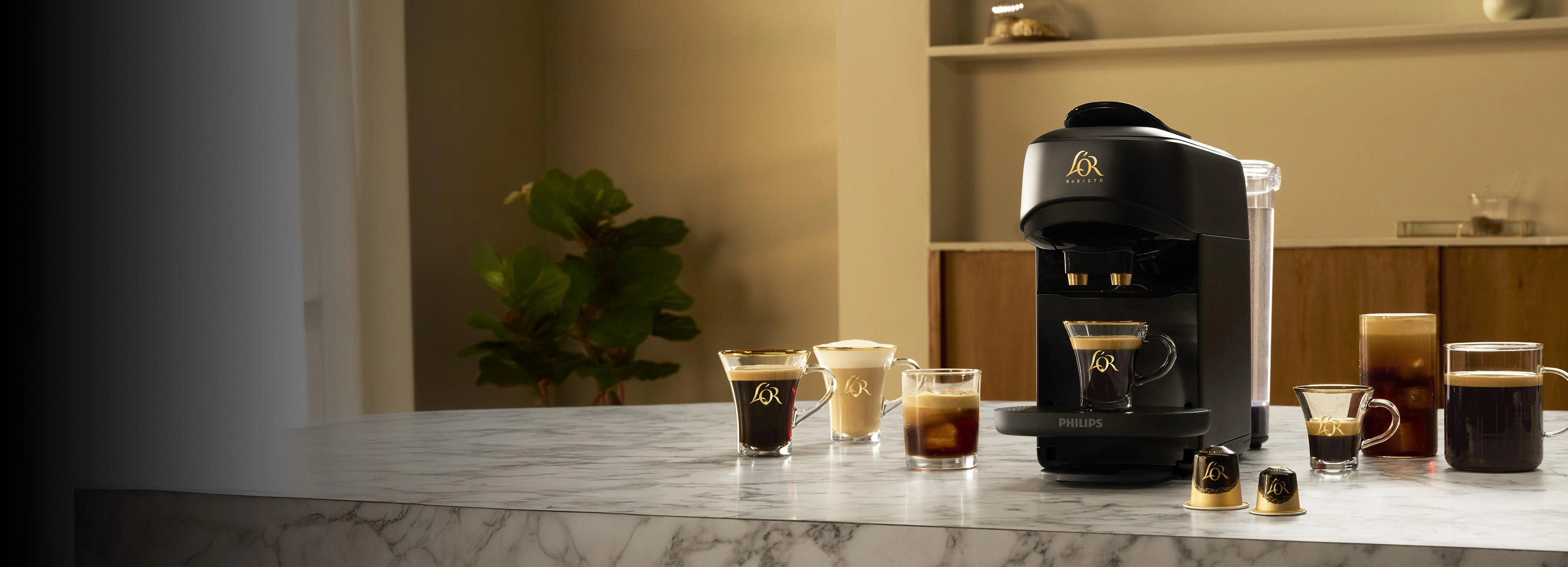 Máquina de café L'OR BARISTA y varias tazas de café sobre una encimera de mármol.