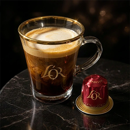 Taza de espresso L'OR en una mesa con cápsulas de café colocadas al lado