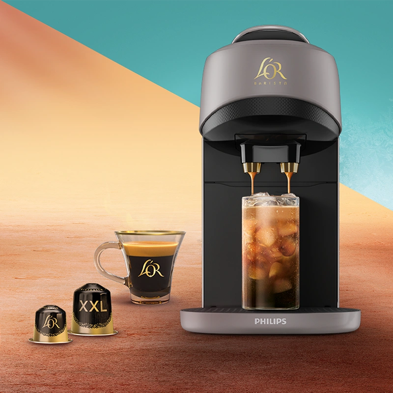 L'OR BARISTA Absolu coffee machine next to L'OR Espresso coffee capsules and a crema-rich coffee cup