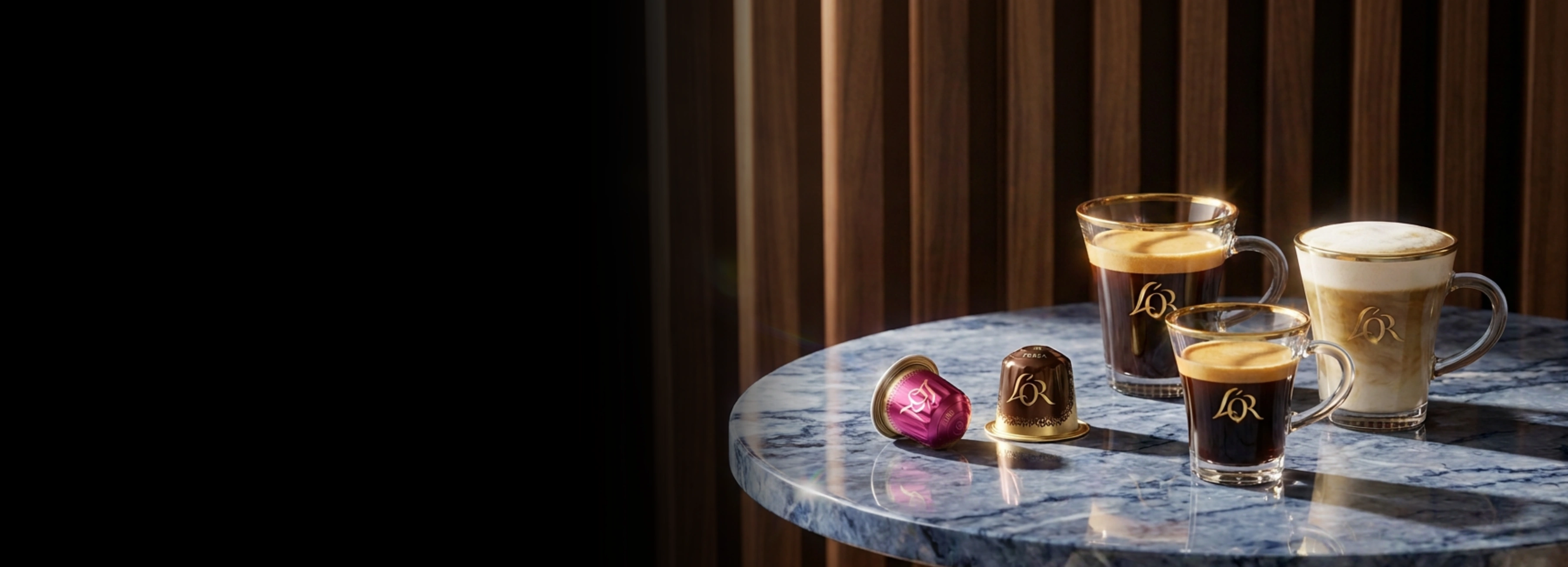 Assorted coffee drinks and L'OR capsules on a marble table against a dark wooden background.