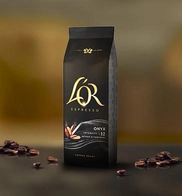 Single black L’OR coffee bean bag surrounded by roasted coffee beans.
