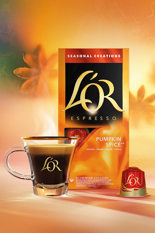 Espresso cup, seasonal product Pumpkin Spice pack and capsules in an autumnal background.