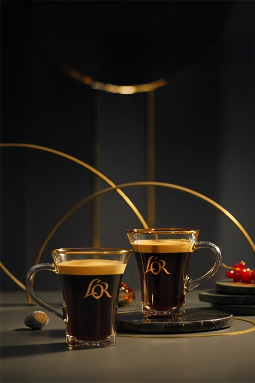Two L'OR lungo cups on a dark and elegant table.