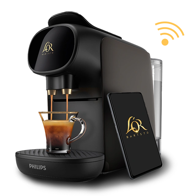 Black L’OR BARISTA Creatif machine pouring a single espresso, with a smartphone displaying the L’OR logo placed beside it.