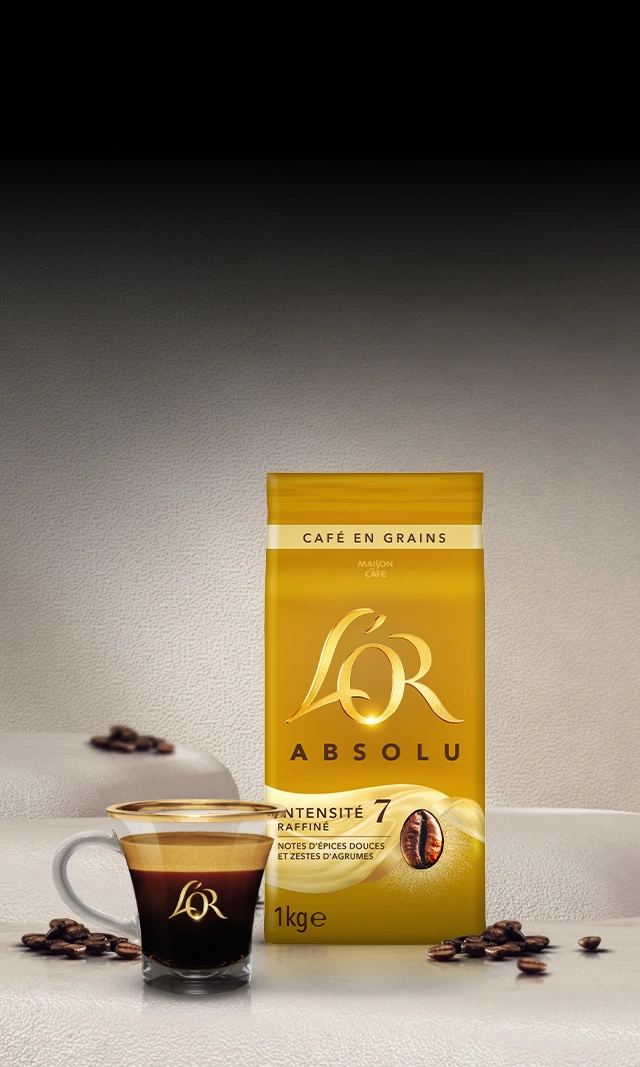 A L'OR Espresso-branded crema-rich coffee cup next to a pack of coffee beans on a tabletop