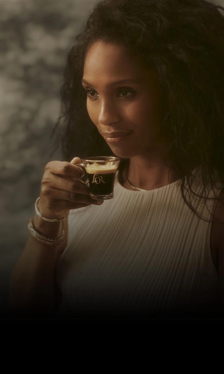 A woman carrying a cup of rich L'OR Espresso coffee